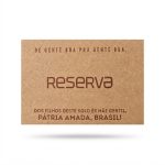 Etiqueta retangular de Zetex marrom claro com o logotipo do pica-pau e a palavra Reserva gravados em baixo relevo.