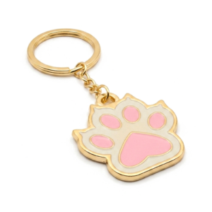 Chaveiro personalizado em metal dourado com argola no topo e aplique em formato de pata de animal com detalhe em resina rosa.